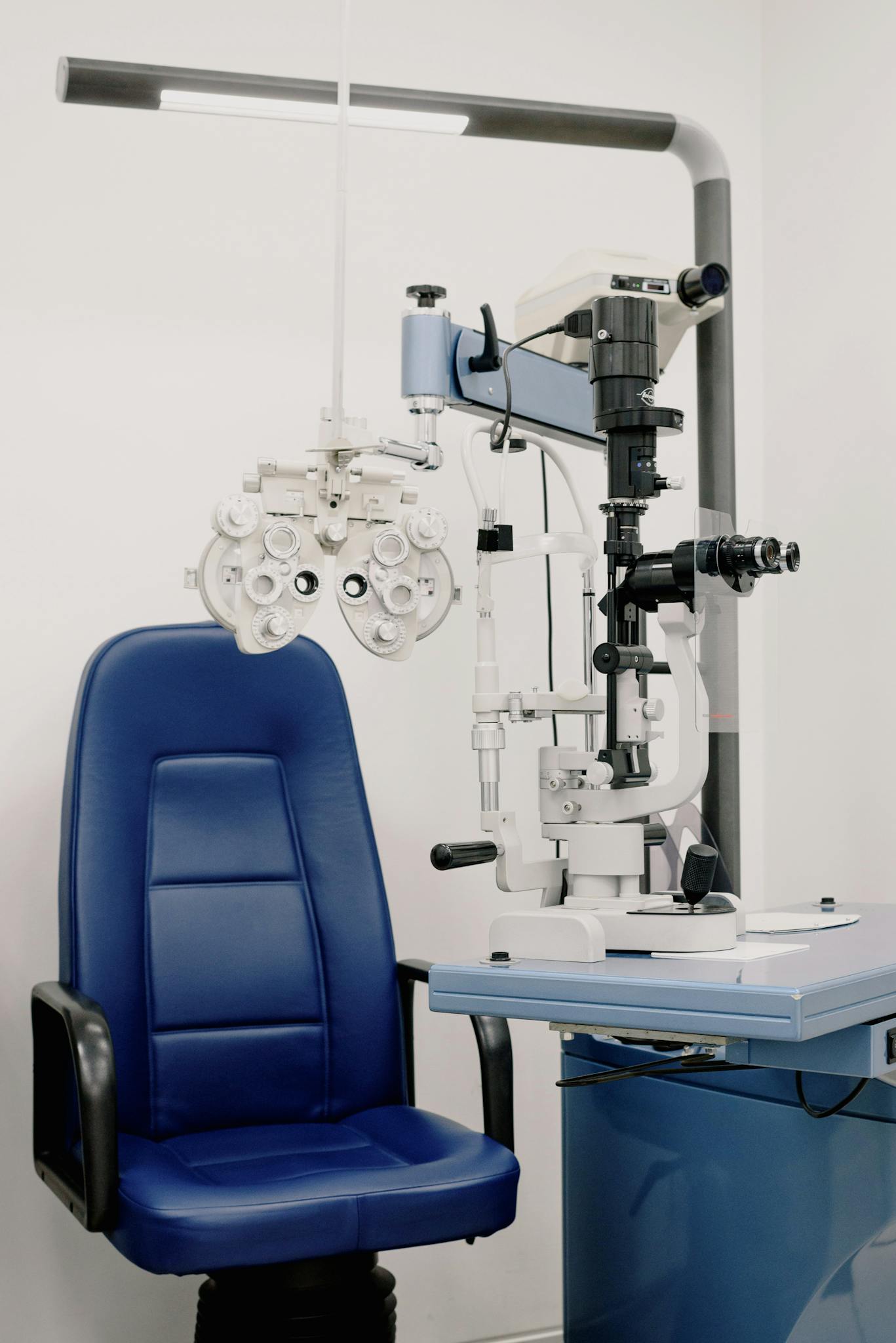 Interior of modern medical office equipped with chair and phoropter for treatment and checking eyesight